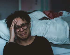 Woman crying next to bed needing hypnotherapy for relationship issues